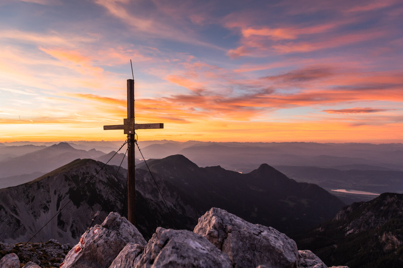 <p>Sonnenaufgang hinter einem Gipfelkreuz in den Karawanken im Kärntner Rosental.</p>